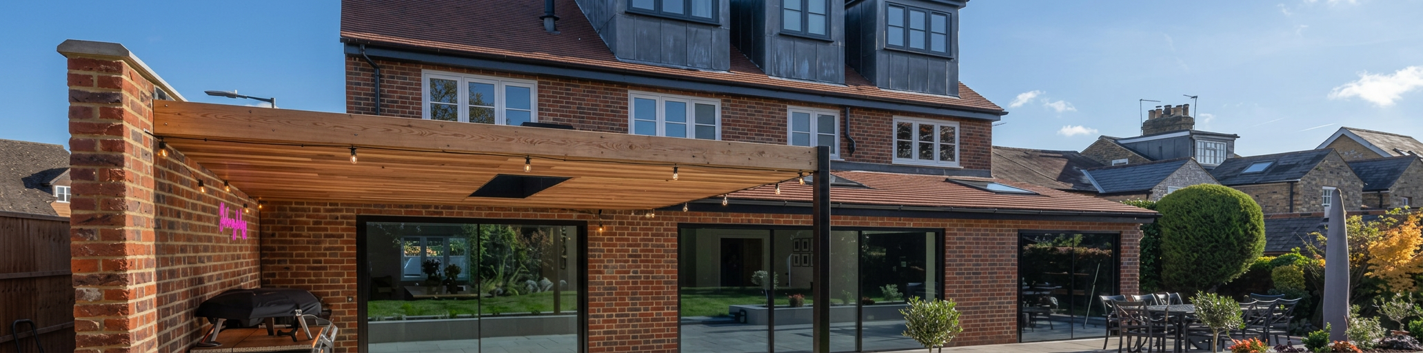 A beautifully renovated brick home with a large extension, dormer windows and landscaped garden